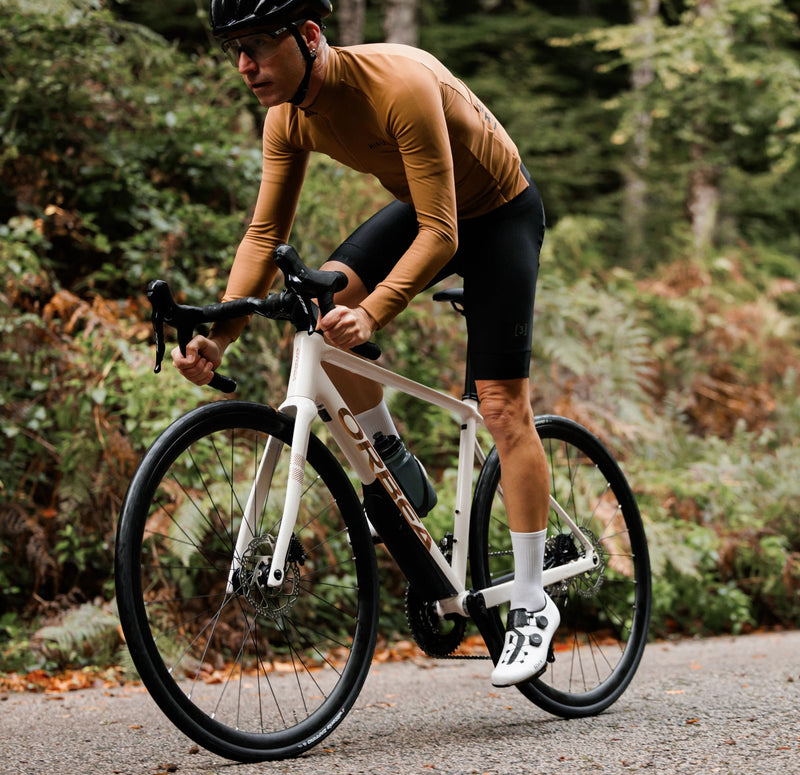 Maður hjólar upp brekku á flottu hvítu Orbea Avant götuhjóli