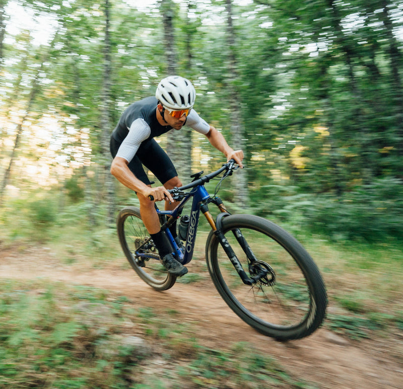Fjallahjólari brunar um á flottu bláu Orbea Oiz fulldempuðu XC fjallahjóli