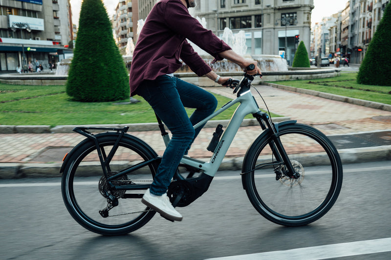 Ljósblátt og svart Orbea Muga fulldempað rafmagnsborgarhjól rúllar um borgina